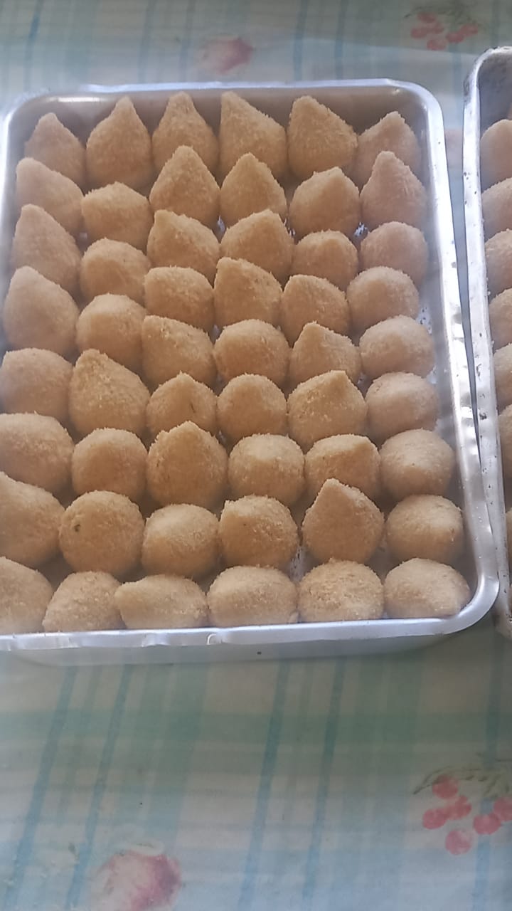 Bandeja cheia de coxinhas empanadas enfileiradas, prontas para fritar