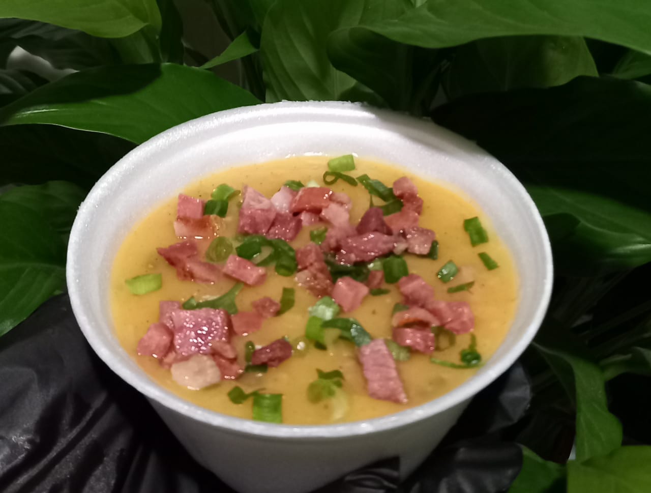 Caldo de mandioca cremoso com bacon e cebolinha em pote branco